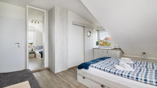 a white bedroom with a bed and a bathroom at Surf camp in Krynica Morska