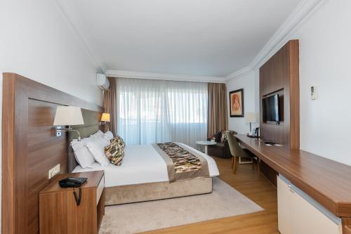 a hotel room with a large bed and a desk at Kenzi Basma in Casablanca