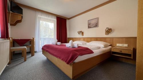 a bedroom with a bed with a red blanket on it at Berghotel Türlwand in Ramsau am Dachstein