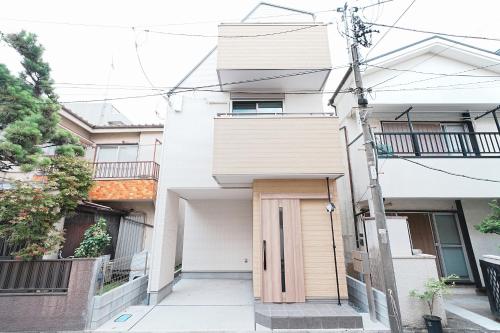 a white building with a wooden door in front of it at Degere in Tokyo