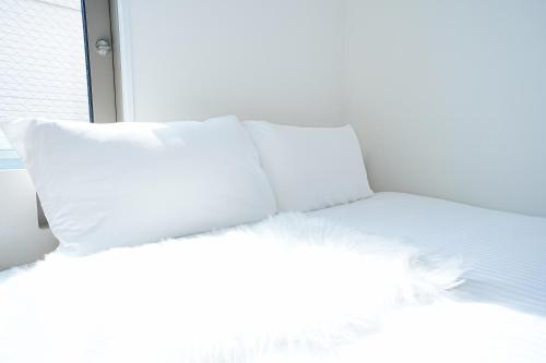 a white bed with four pillows on top of it at Degere in Tokyo