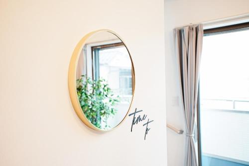 a round mirror hanging on a wall in a bathroom at Degere in Tokyo