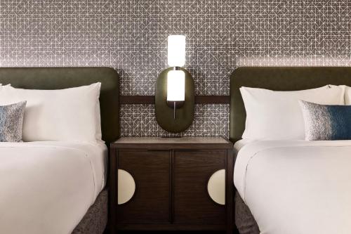 two beds with white sheets and a mirror between them at Renaissance Phoenix Glendale Hotel & Conference Center in Glendale