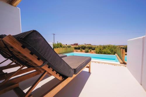 a rocking chair on a balcony with a swimming pool at Aegean Hospitality in Mýkonos City