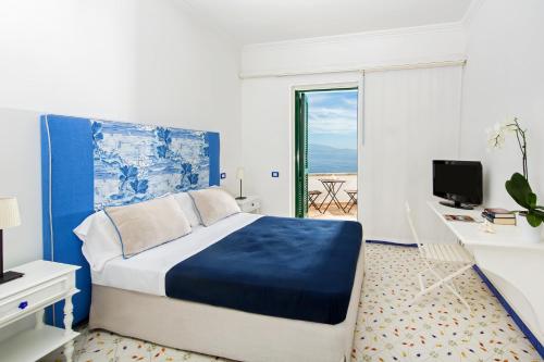 um quarto com uma cama, uma secretária e uma janela em Hotel Le Terrazze em Conca dei Marini