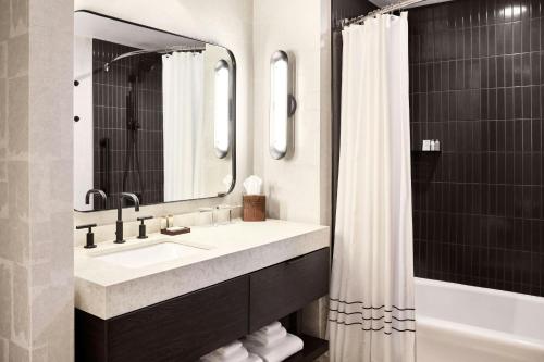 a bathroom with a sink and a mirror and a shower at Renaissance Phoenix Glendale Hotel & Conference Center in Glendale