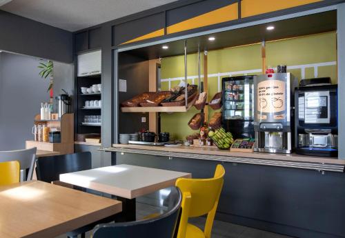 a restaurant with a counter with tables and chairs at B&B HOTEL Avignon 2 in Le Pontet