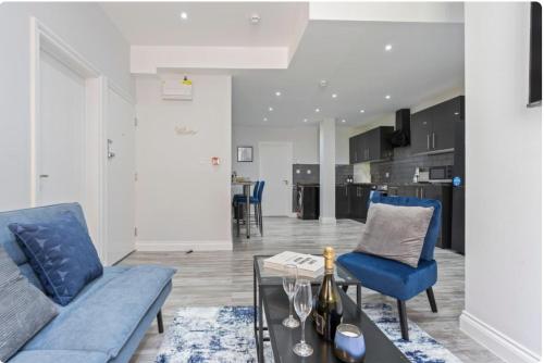 a living room with a blue couch and a glass table at Modern Coastal Apartment In Central Location in Harwich