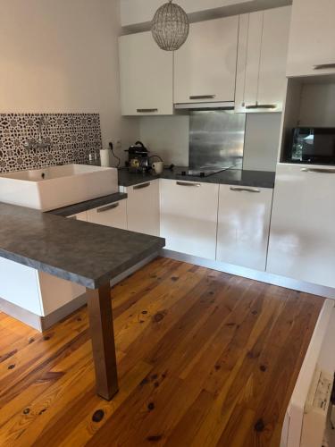 une cuisine avec des armoires blanches et un plancher en bois dans l'établissement Grain de folie, à Mulhouse