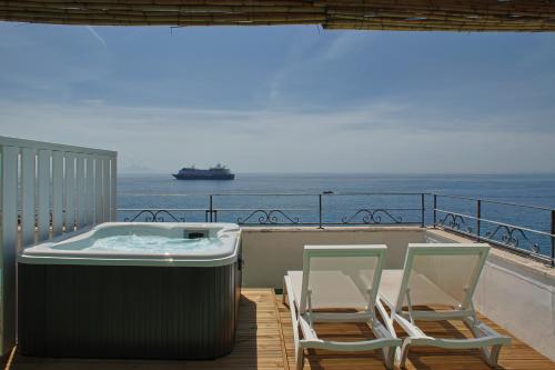 two chairs and a hot tub on a balcony with the ocean at Hotel Aurora in Amalfi