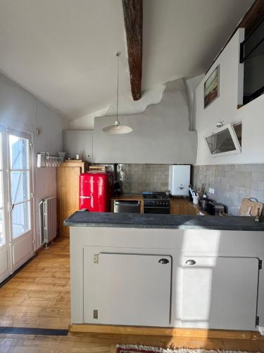 La cuisine est équipée de placards blancs et d'un réfrigérateur rouge. dans l'établissement Le Petit Duplex du Quartier-Haut, à Sète