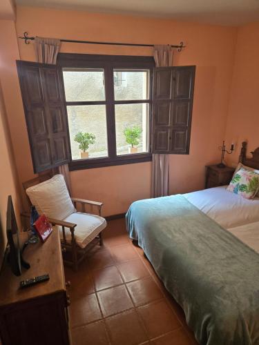 a bedroom with a bed and a chair and a window at Hotel el Castellar in Moscardón