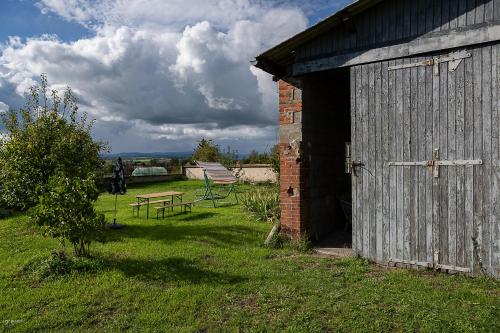 a barn with a table and a bench in a field at C'est Chouette le gîte ! in Saint-Jodard