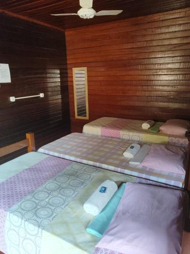 two twin beds in a room with wooden walls at Pousada Vila da Praia in Santarém