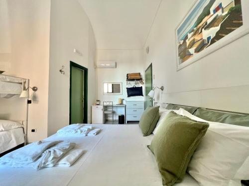 a bedroom with a large white bed with green pillows at Hotel Posta in Siracusa