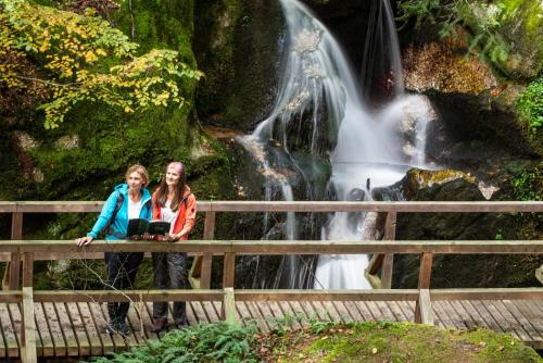 two women standing on a bridge in front of a waterfall at Schatz.Kammer Burg Kreuzen in Bad Kreuzen