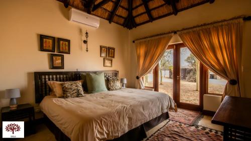 ein Schlafzimmer mit einem Bett und einem großen Fenster in der Unterkunft Zebula Golf and Wildlife Estate - Owl's Haven Pax 10 - Moi Signature Luxury villa in Mabula