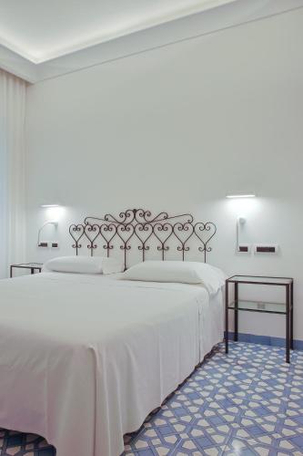 a bedroom with a large white bed and a table at Hotel Aurora in Amalfi