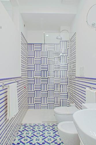 a bathroom with a toilet and two sinks and ailed wall at Hotel Aurora in Amalfi