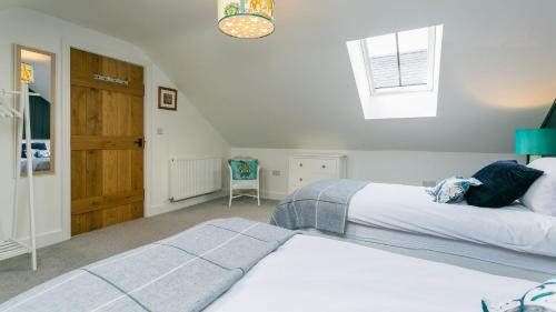 a bedroom with two beds and a window and a chair at Cleifiog Fawr in Valley