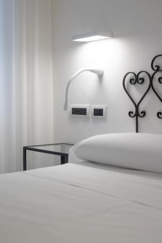 a white bedroom with a bed and a lamp at Hotel Aurora in Amalfi