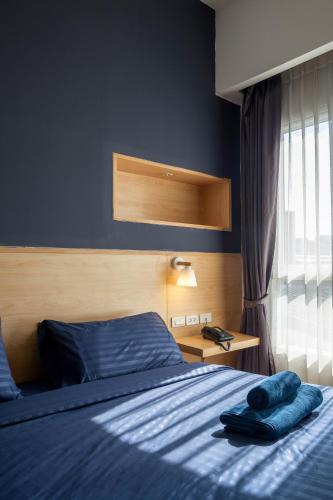 a bedroom with a bed with blue sheets and a window at GP House Express Sukhumvit 81 in Bangkok