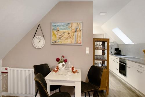 a kitchen with a table and chairs and a clock on the wall at Dünenblick in Prerow
