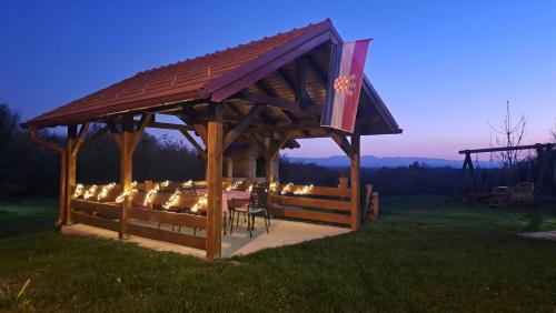 a wooden gazebo with a table and lights at Kokotova hiža in Gornja Konjšćina