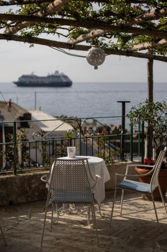 a table and chairs on a balcony with a cruise ship at Hotel Aurora in Amalfi
