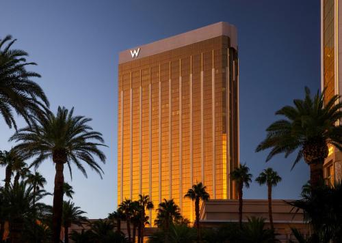 a tall yellow building with palm trees in front of it at W Las Vegas in Las Vegas