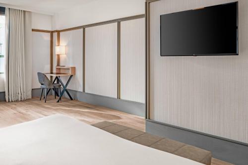 a hotel room with a flat screen tv on a wall at AC Hotel Avenida de América by Marriott in Madrid