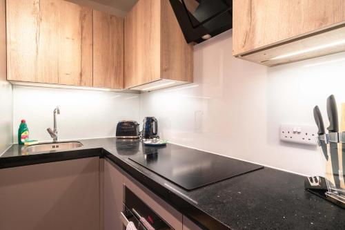 a kitchen with wooden cabinets and a black counter top at Stunning 2BED Flat in Central Location w Security in Manchester