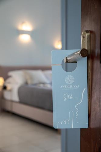 a door with a sign on it in front of a bed at Aneroussa Beach Hotel in Batsi