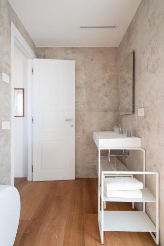 a white bathroom with a sink and a mirror at Alfiere Arc Loft by Klodge in Olbia