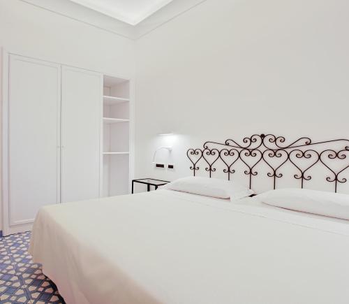 a white bedroom with a large bed with white sheets at Hotel Aurora in Amalfi
