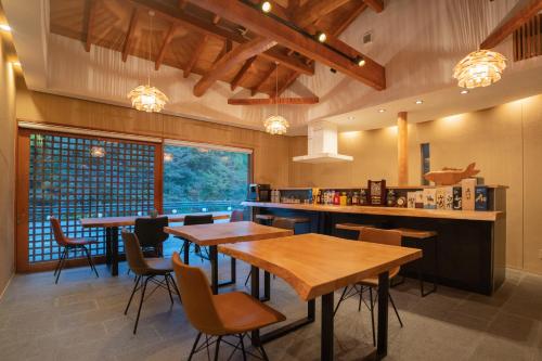 Un restaurante con mesas y sillas de madera y un mostrador. en ホテル郷, en Uda