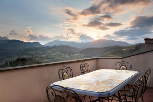 a table and chairs on a balcony with a view of mountains at Renaissance Tuscany Il Ciocco Resort & Spa in Barga