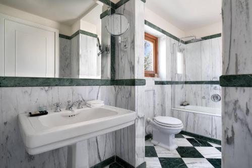 a white bathroom with a sink and a toilet at Renaissance Tuscany Il Ciocco Resort & Spa in Barga