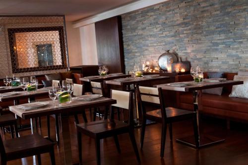 a restaurant with wooden tables and chairs and a brick wall at Renaissance Tuscany Il Ciocco Resort & Spa in Barga