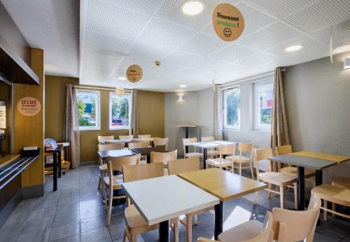 une salle à manger avec tables, chaises et fenêtres dans l'établissement B&B HOTEL Villeneuve Loubet Plage, à Villeneuve-Loubet