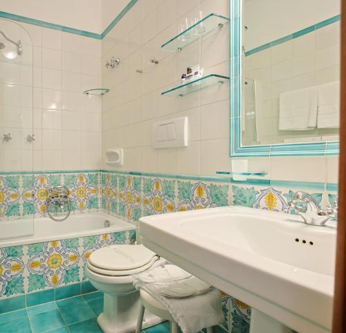 a bathroom with a sink and a toilet and a tub at Hotel Aurora in Amalfi
