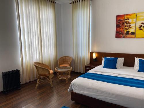 a hotel room with a bed and two chairs at Villa Cassandra in Nuwara Eliya