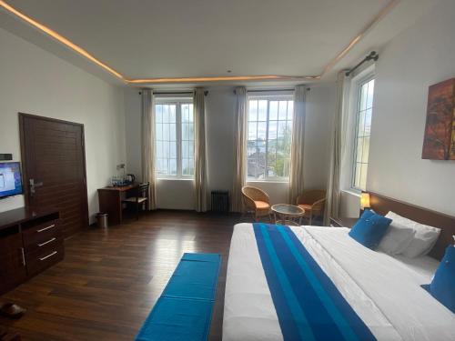 a bedroom with a bed and a tv and some windows at Villa Cassandra in Nuwara Eliya
