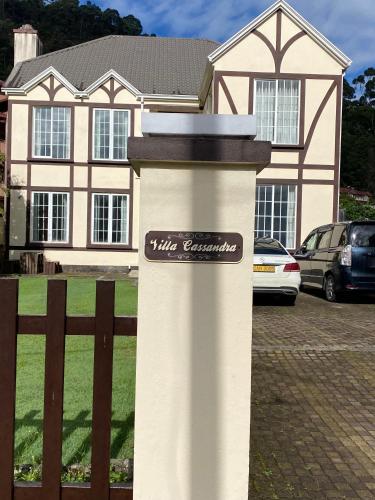 a house with a white column with a sign on it at Villa Cassandra in Nuwara Eliya