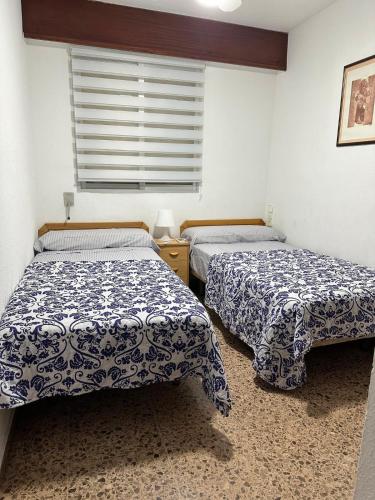 two beds in a room with a window at Los Olivos BB1 in Faro de Cullera