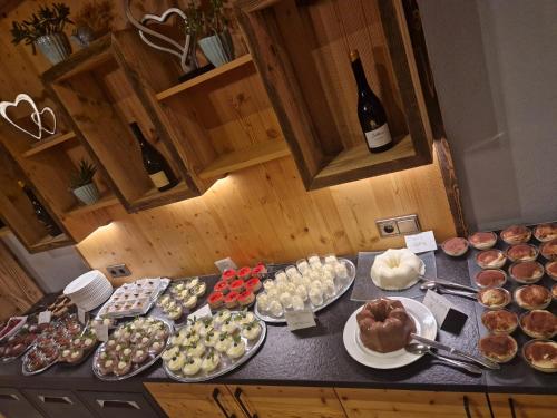a table with a bunch of desserts and a bottle of wine at Hotel Tonnerhof in Racines