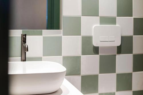 a bathroom with a white sink and green and white tiles at VLC HOST - Reina 168 in Valencia