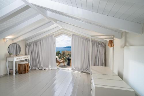Habitación blanca con ventana grande y mesa. en THALASSA VIEW RESIDENCE, en Argostoli
