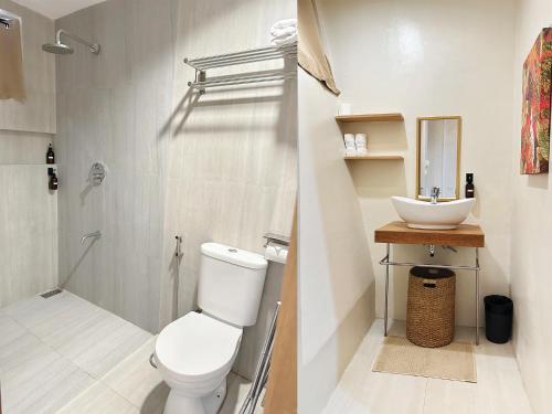 a white bathroom with a toilet and a sink at Barco El Nido Hotel in El Nido
