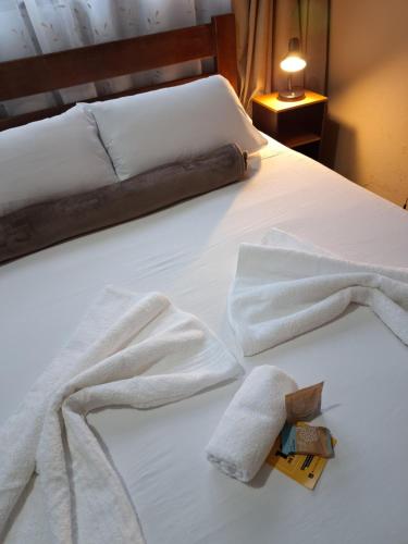 a white bed with two towels on it at Chapéu de Sol - Área Gourmet, TV, Internet, Roupas de Cama e Banho, Jardim, Horta e Pomar in Ilha Comprida